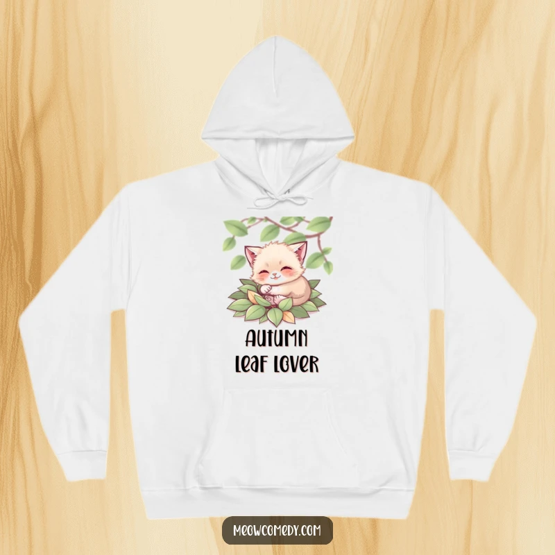 Funny Cat Hoodie: A tiny, contented cat rolling in a soft pile of vibrant autumn leaves, radiating warmth and happiness.